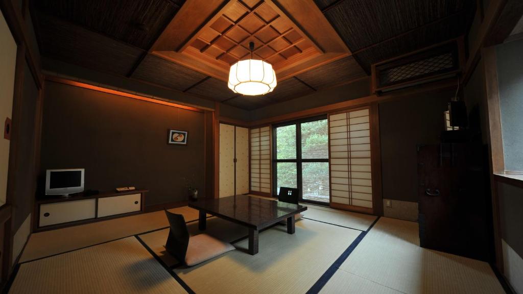 - un salon avec une table et une télévision dans l'établissement Yuzuya Ryokan - Adult Only, à Kyoto
