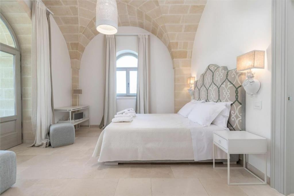 une chambre blanche avec un grand lit et une fenêtre dans l'établissement Villa Bellavista by Raro Villas, à Ostuni