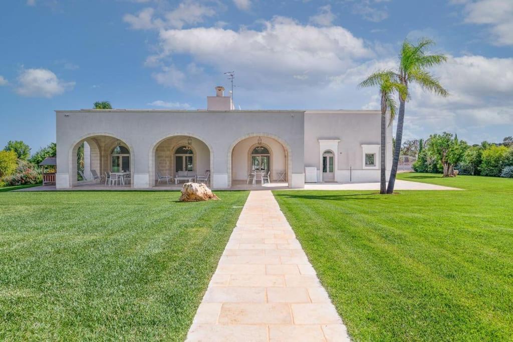 une grande maison blanche avec une cour gazonnée dans l'établissement Villa Bellavista by Raro Villas, à Ostuni