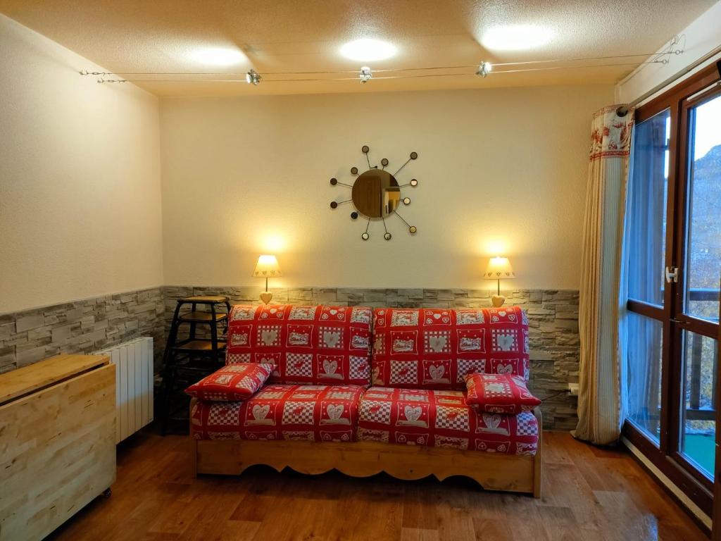 - un salon avec un canapé rouge et une horloge murale dans l'établissement Pluton B63, à Les Deux Alpes