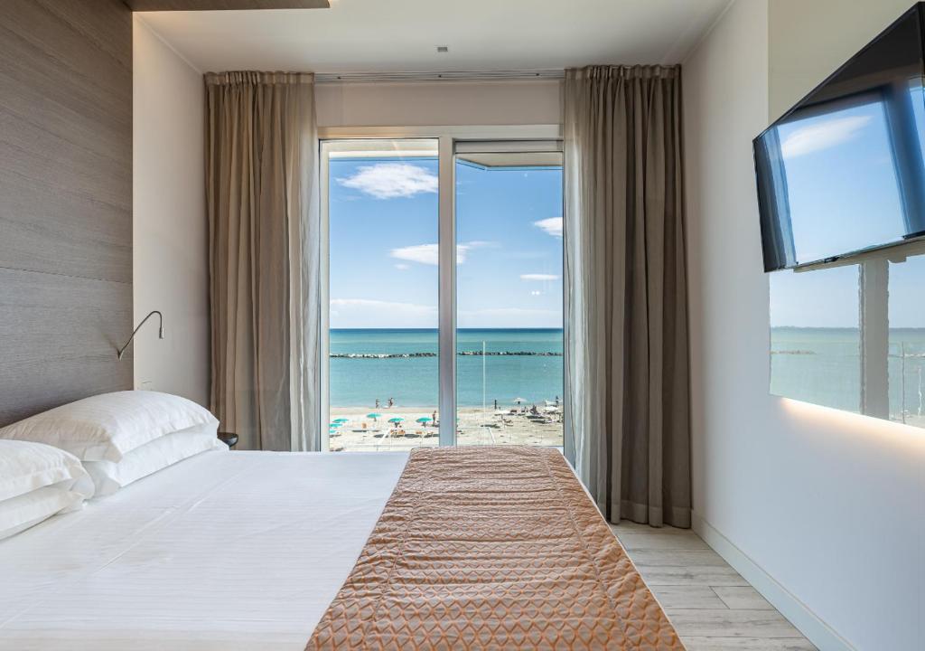 une chambre avec un lit et une vue sur la plage dans l'établissement Hotel Savini, à Bellaria-Igea Marina 100 autres photos