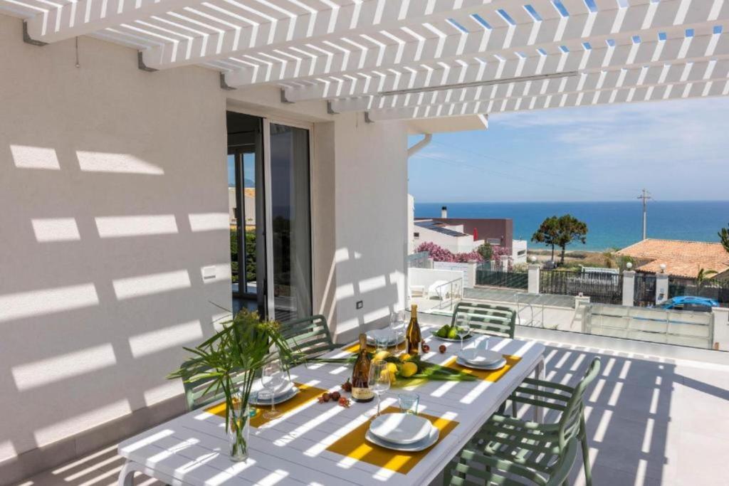 - une table blanche avec des chaises sur une terrasse donnant sur l'océan dans l'établissement Villa Taliala, à Alcamo Marina