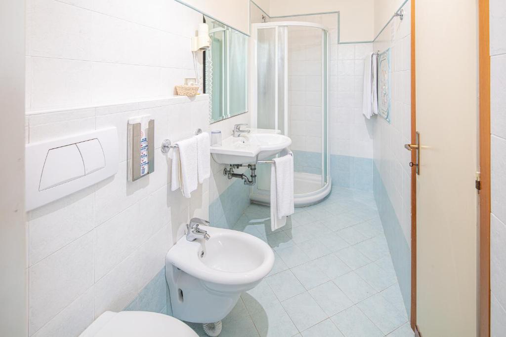 une salle de bain blanche avec toilettes et lavabo dans l'établissement Hotel Alexander, à Bibione