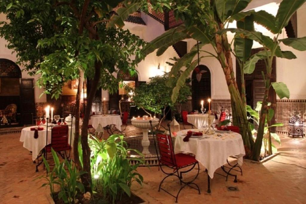 un restaurant avec des tables, des chaises et des arbres dans l'établissement Riad ILayka, à Marrakech