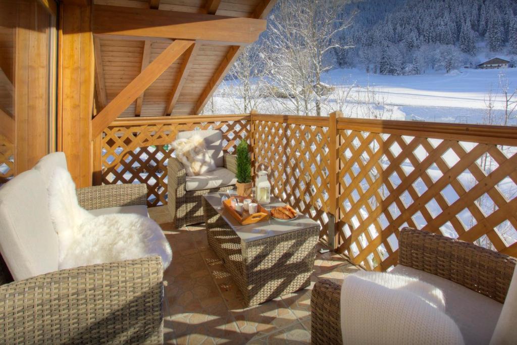 - une terrasse couverte avec des chaises, une table et une neige dans l'établissement Dorealp - OVO Network, à La Clusaz