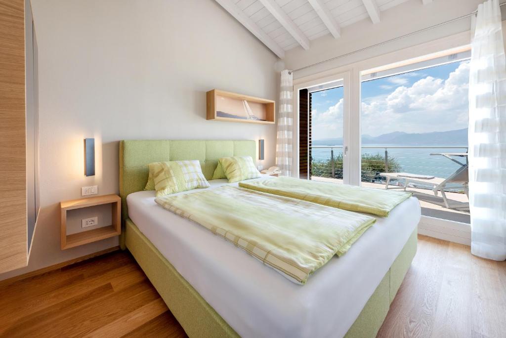une chambre avec un grand lit et une grande fenêtre dans l'établissement Villa Vela, à Torri del Benaco
