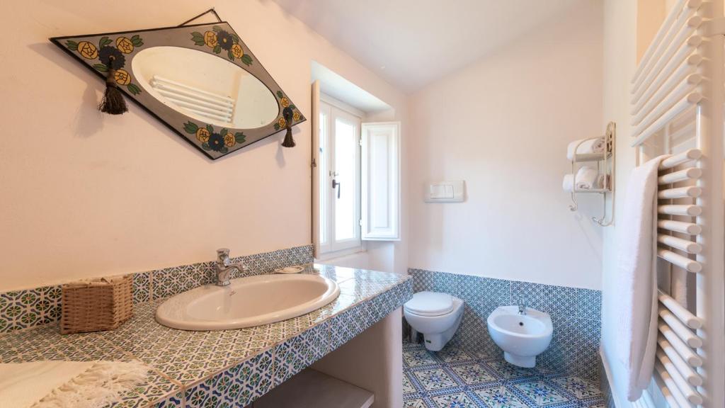 une salle de bain avec un lavabo, des toilettes et un miroir dans l'établissement LA CASA NEI VIGNETI 10, Emma Villas, à Catignano