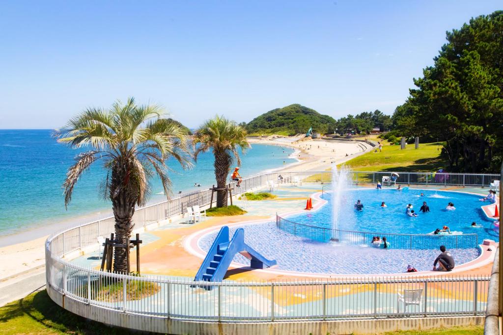 un parc aquatique avec un toboggan et une plage dans l'établissement Kyukamura Shikanoshima, à Fukuoka