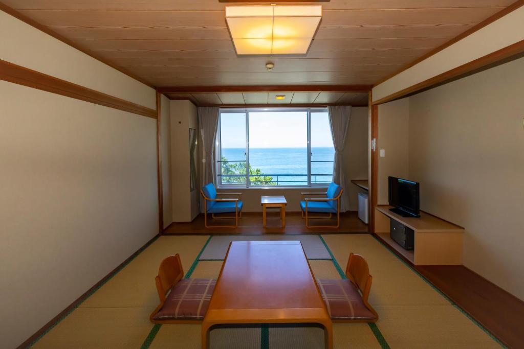 une pièce avec une table, des chaises et une fenêtre dans l'établissement Kyukamura Shikanoshima, à Fukuoka