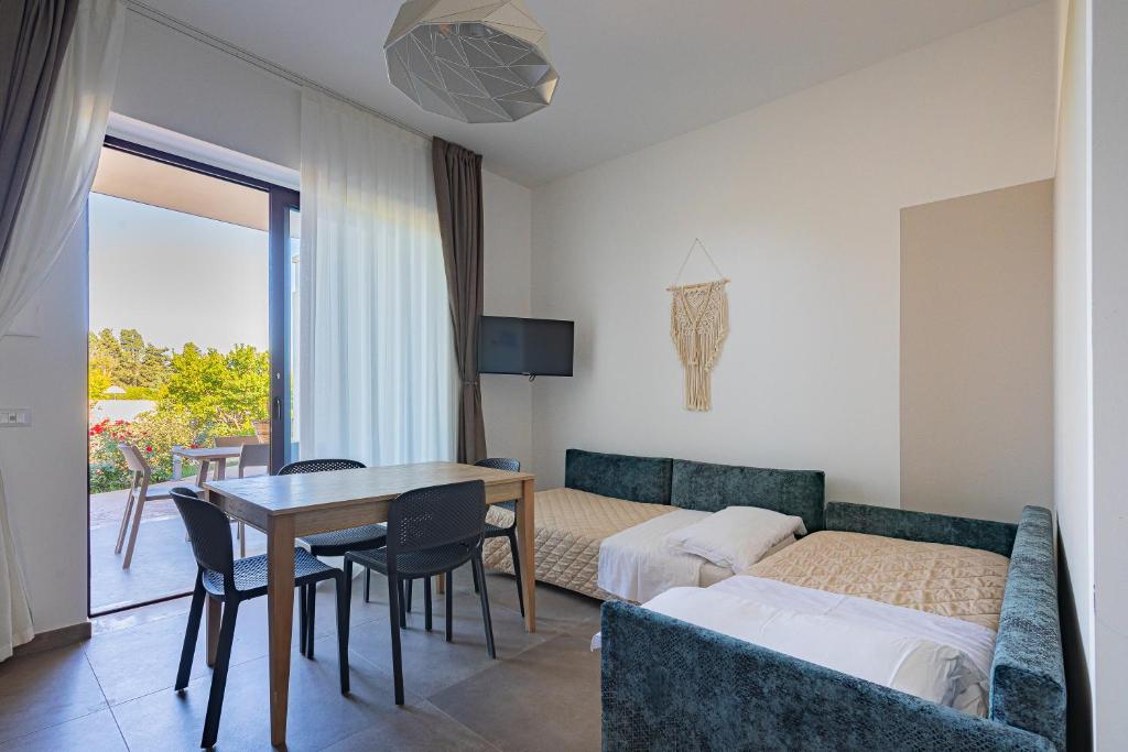 une chambre avec un lit, une table et des chaises dans l'établissement Agriturismo Vigna Corallo, à Otrante