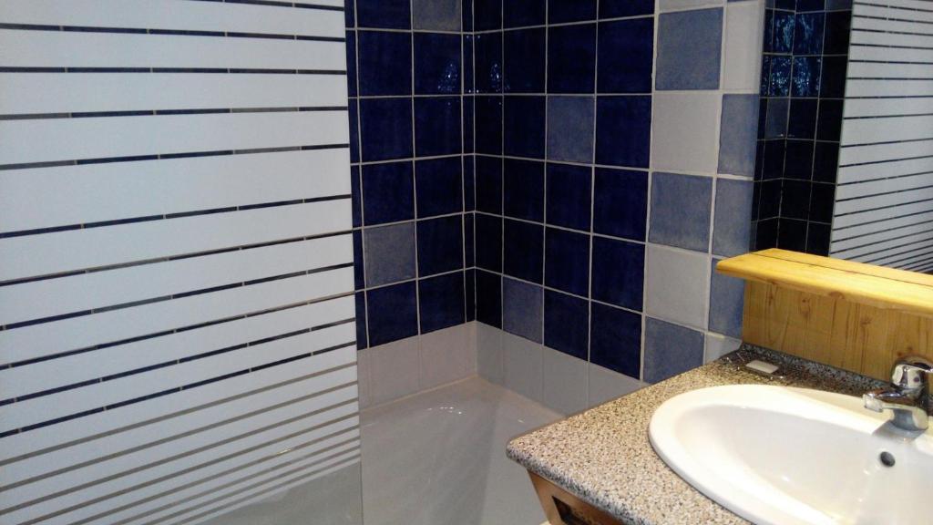 La salle de bains est pourvue d'un lavabo et de carrelage bleu et blanc. dans l'établissement Studio 20 Les Grandes Platières, à Tignes