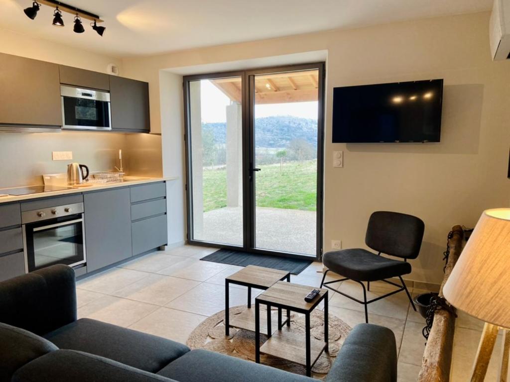un salon avec un canapé et des chaises et une cuisine dans l'établissement Mas de Veyras - Gîtes 5 étoiles en Ardèche, à Lachapelle-sous-Aubenas