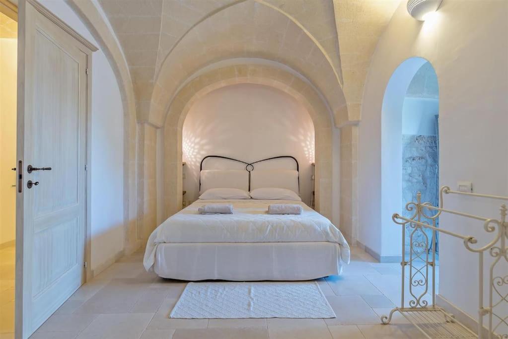 une chambre avec un grand lit dans une pièce blanche dans l'établissement Masseria Il Frantoio by Raro Villas, à Ostuni