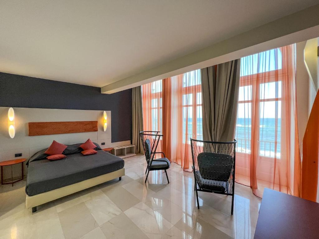 - une chambre avec un lit, des chaises et des fenêtres dans l'établissement Central Gallery Rooms- Palazzo D'Ali' Staiti XIX, à Trapani