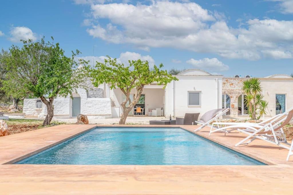 une piscine avec deux chaises et une maison dans l'établissement Bianco Trullo by Raro Villas, à Latiano