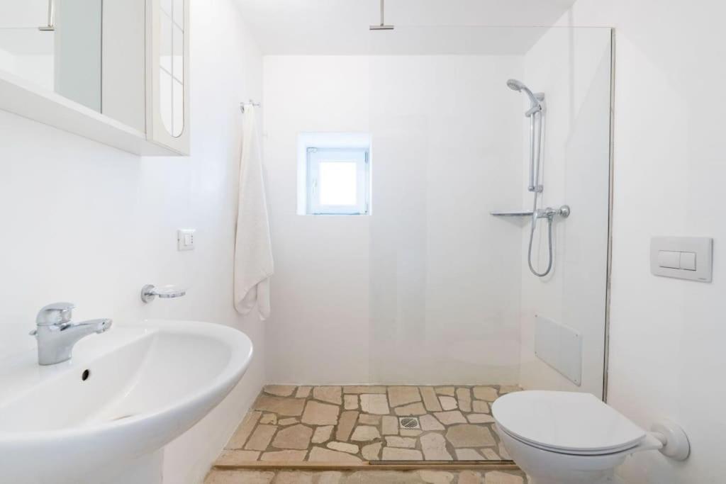 une salle de bain blanche avec un lavabo et des toilettes dans l'établissement Bianco Trullo by Raro Villas, à Latiano