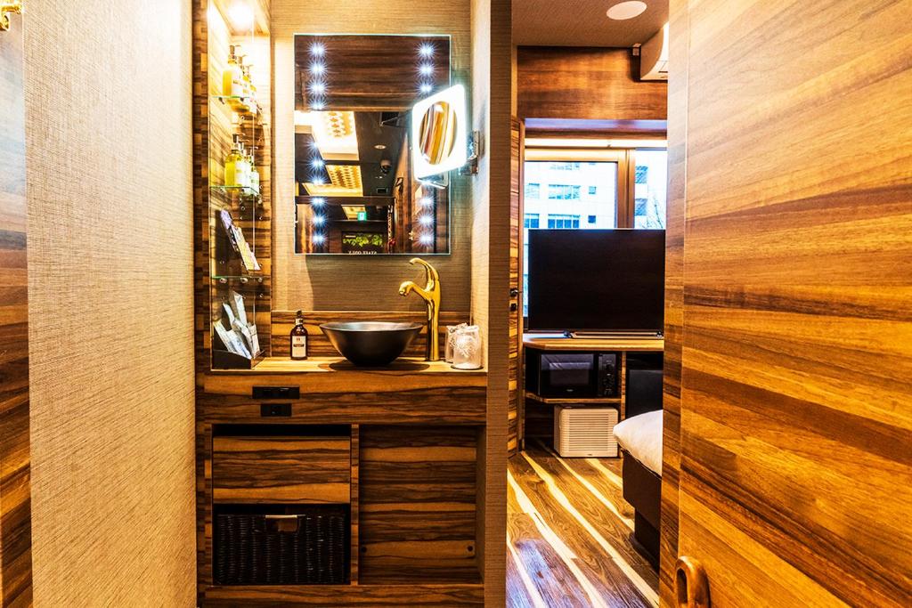 La salle de bains est pourvue d'un lavabo et d'un bureau avec une télévision. dans l'établissement Petit Bali Forest Shinjuku Sanchōme, à Tokyo
