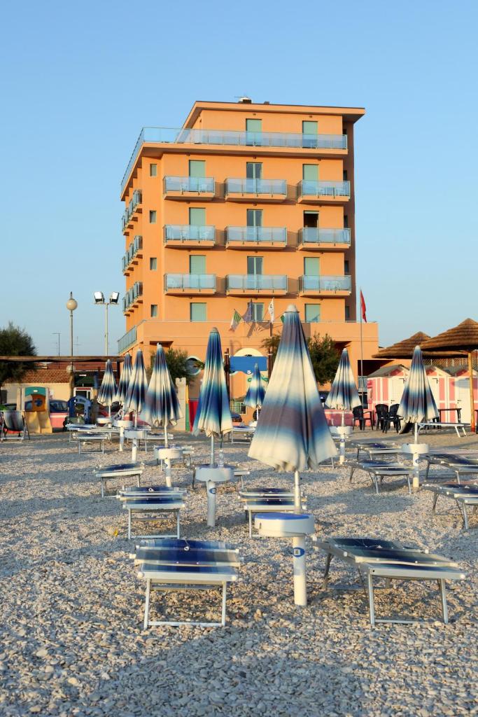 un groupe de chaises et de parasols sur une plage dans l'établissement Abbazia Club Hotel Marotta, à Marotta