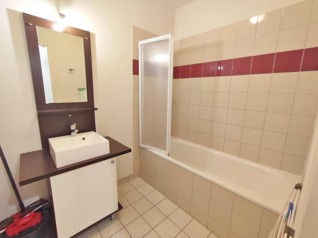 une salle de bain avec un lavabo, une baignoire et un miroir dans l'établissement Le Marmotton, T2, centre Luchon, wifi, casier à skis, ascenseur, 5 personnes, à Luchon