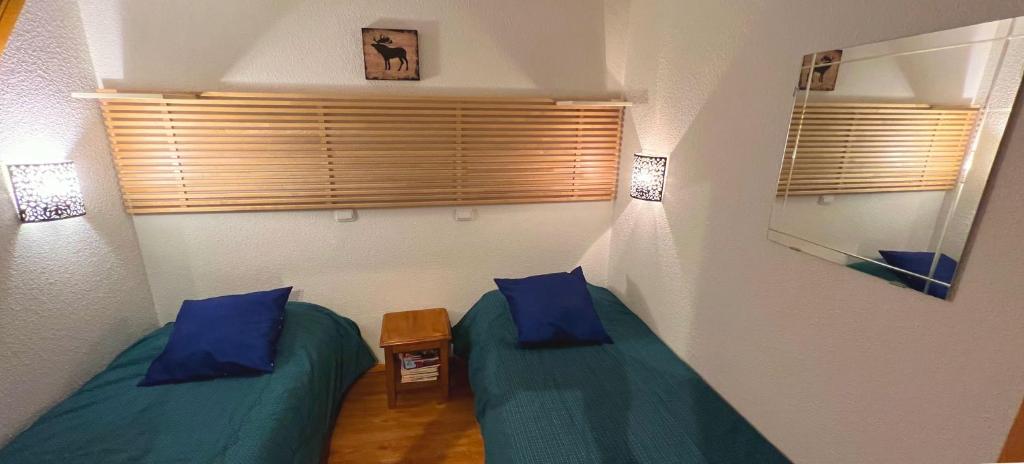 - 2 lits jumeaux dans une chambre avec des oreillers bleus dans l'établissement Le Skisun - Massif et Parc national des Ecrins - Puy Saint Vincent 1800, à Puy-Saint-Vincent