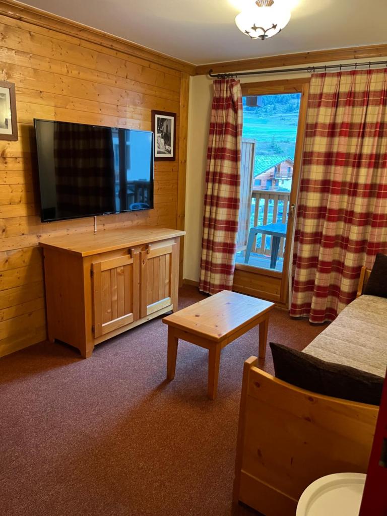 un salon avec une télévision à écran plat et un canapé dans l'établissement Les alpages location appartement 108, à Lanslebourg-Mont-Cenis