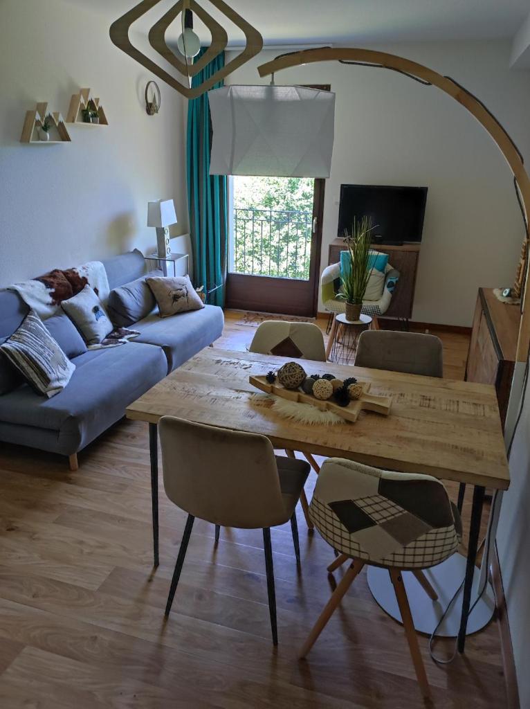 un salon avec une table et un canapé bleu dans l'établissement T3 cosy au Jardin du Ramel, à Luchon