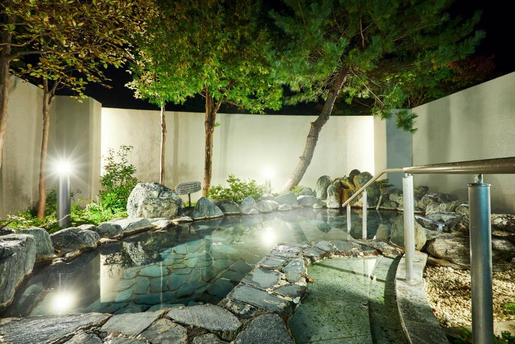 un bassin d'eau avec des rochers et des arbres dans l'établissement KAMENOI HOTEL SHIOBARA Dog Friendly Hotel, à Nasushiobara