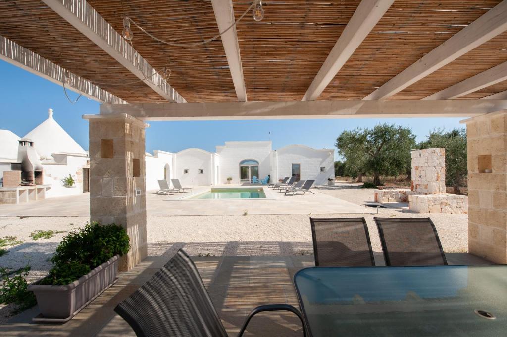 un patio avec une table et des chaises et une piscine dans l'établissement Trullo Amelie, à Ostuni
