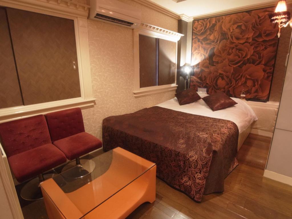 une chambre d'hôtel avec un lit et une chaise dans l'établissement SKYROAD Adult Only, à Tokyo