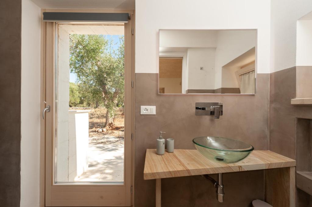 La salle de bains est pourvue d'un lavabo en verre sur un comptoir. dans l'établissement Trullo Amelie, à Ostuni