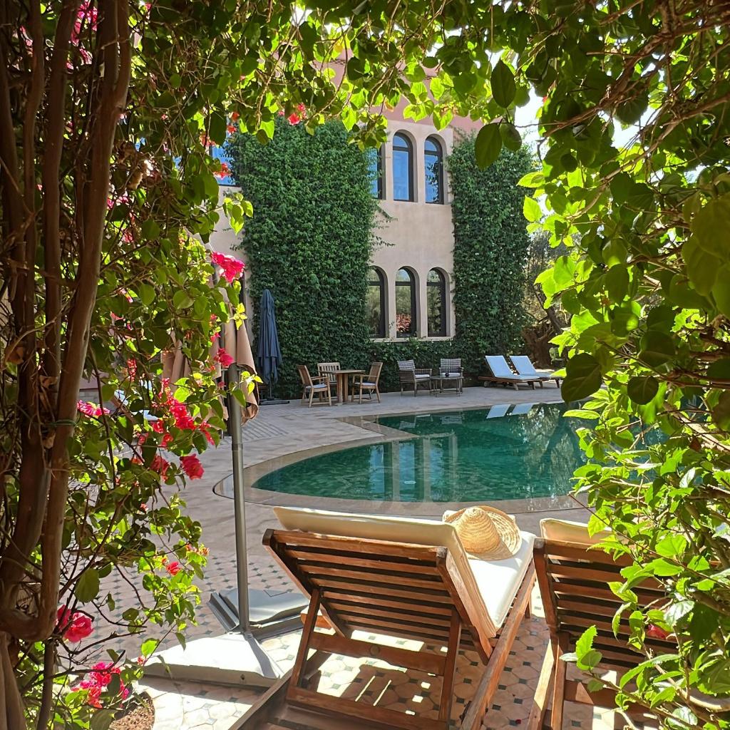 une piscine avec deux chaises et un bâtiment dans l'établissement Al Fassia Aguedal, à Marrakech 37 autres photos