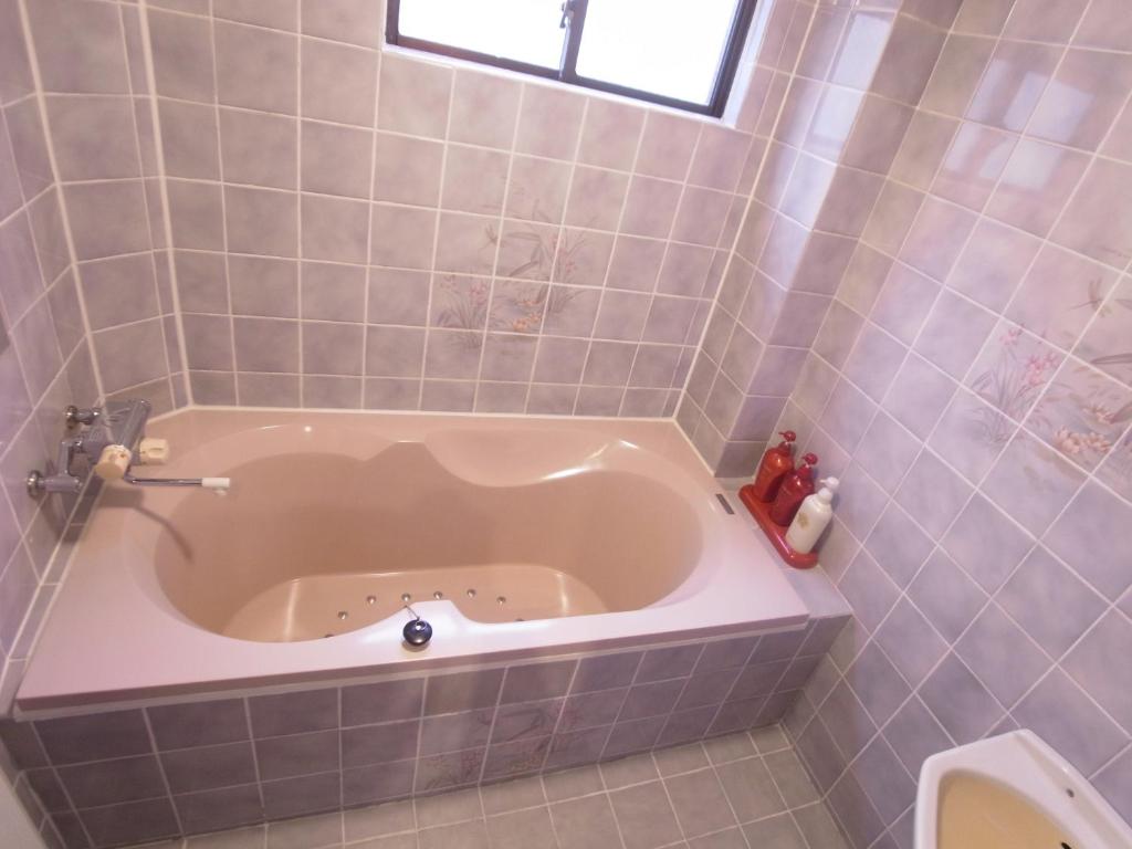 La salle de bains carrelée est pourvue d'une baignoire et de toilettes. dans l'établissement SKYROAD Adult Only, à Tokyo