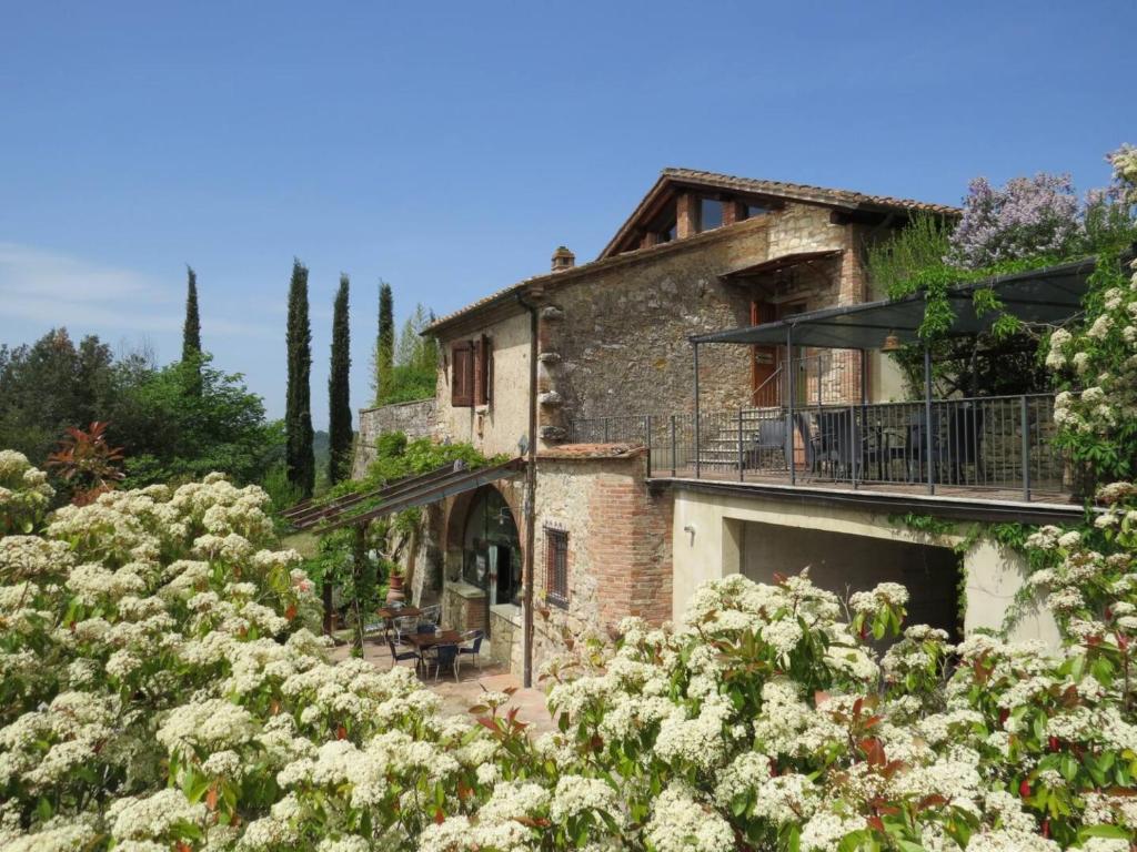 une ancienne maison en pierre avec un balcon et des fleurs dans l'établissement Villa Il Fornacino, à Rapolano Terme