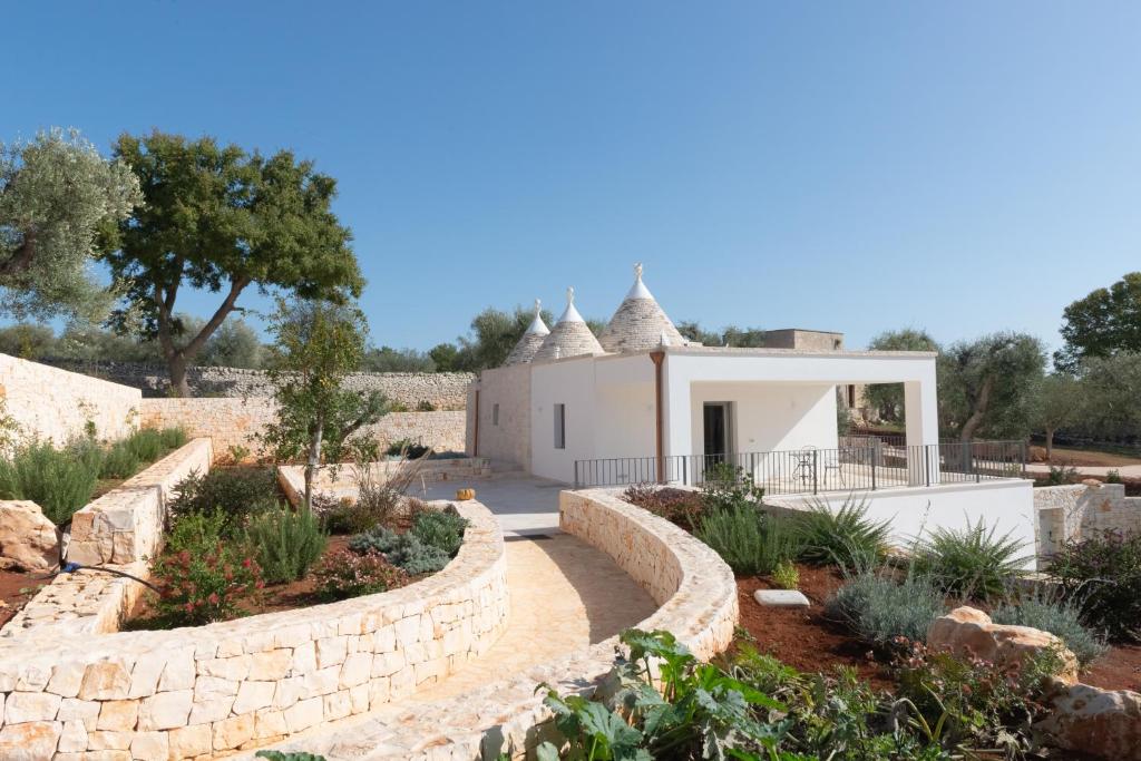 une maison avec un jardin et un mur de pierre dans l'établissement Trullo Mamamè, à Cisternino