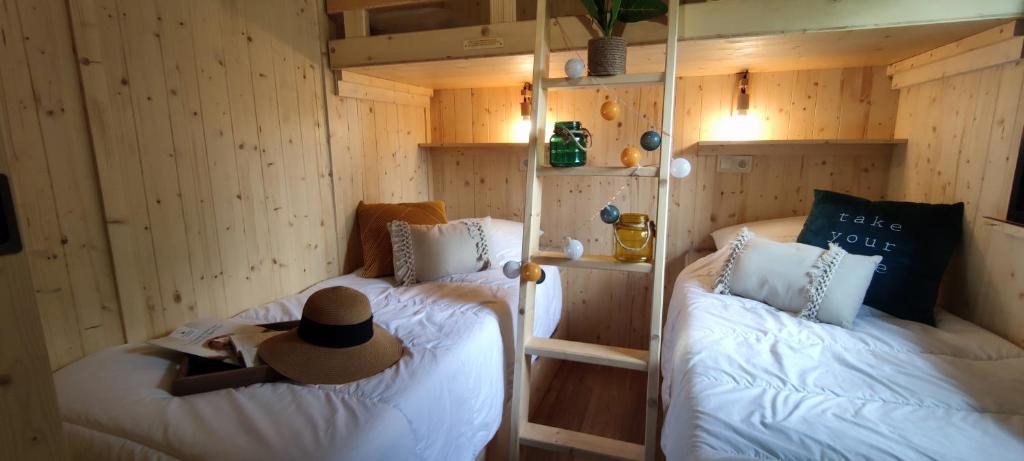 une personne dans un chapeau assise sur deux lits dans une pièce dans l'établissement Camping du Lac, à Marcillac-la-Croisille 37 autres photos