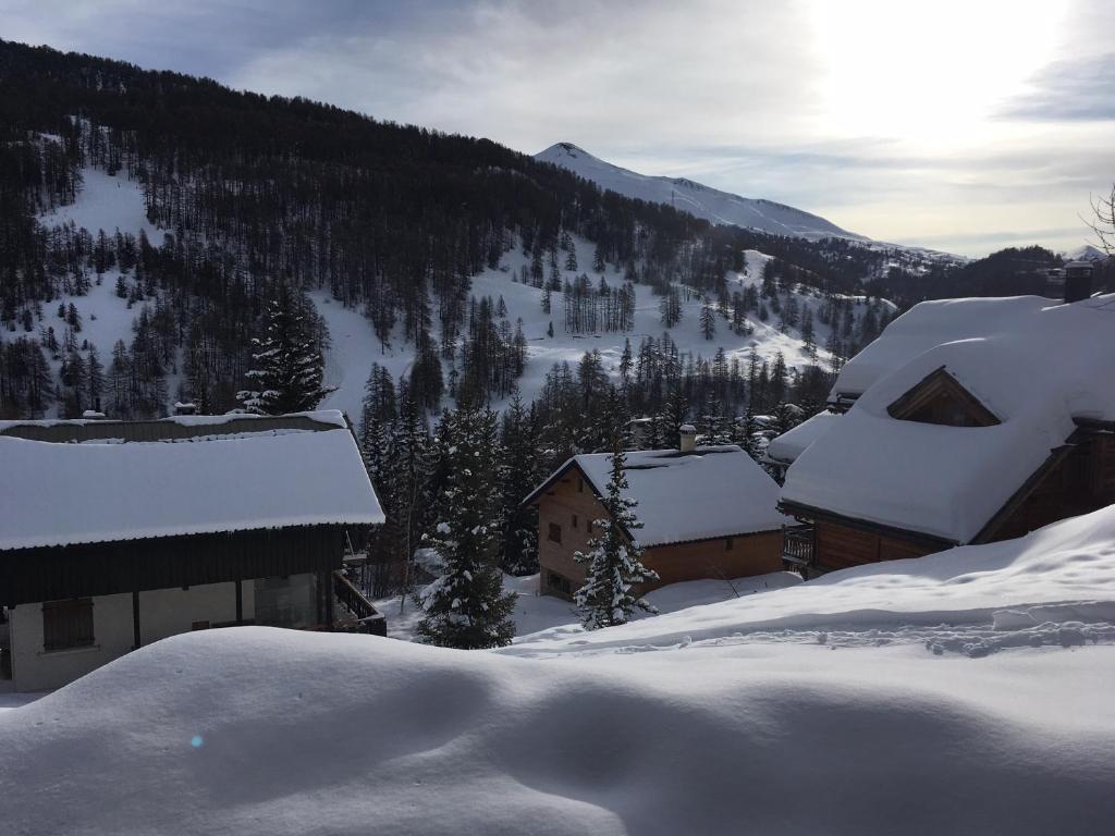 un village recouvert de neige avec des montagnes en arrière-plan dans l'établissement Home Vars. Le studio, à Vars