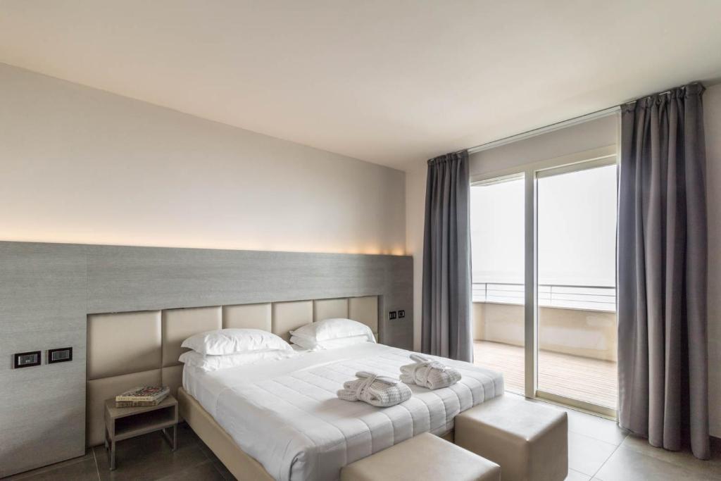 une chambre avec un grand lit et une grande fenêtre dans l'établissement Bellettini Hotel, à Milano Marittima