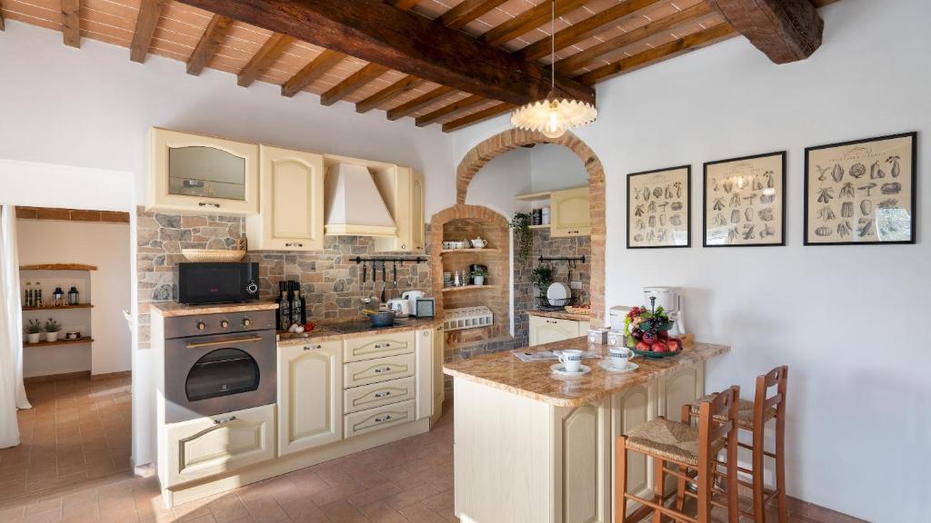 une cuisine avec des armoires blanches et un four à plaques de cuisson dans l'établissement CASA LA FENICE 8&2, Emma Villas, à Pomarance