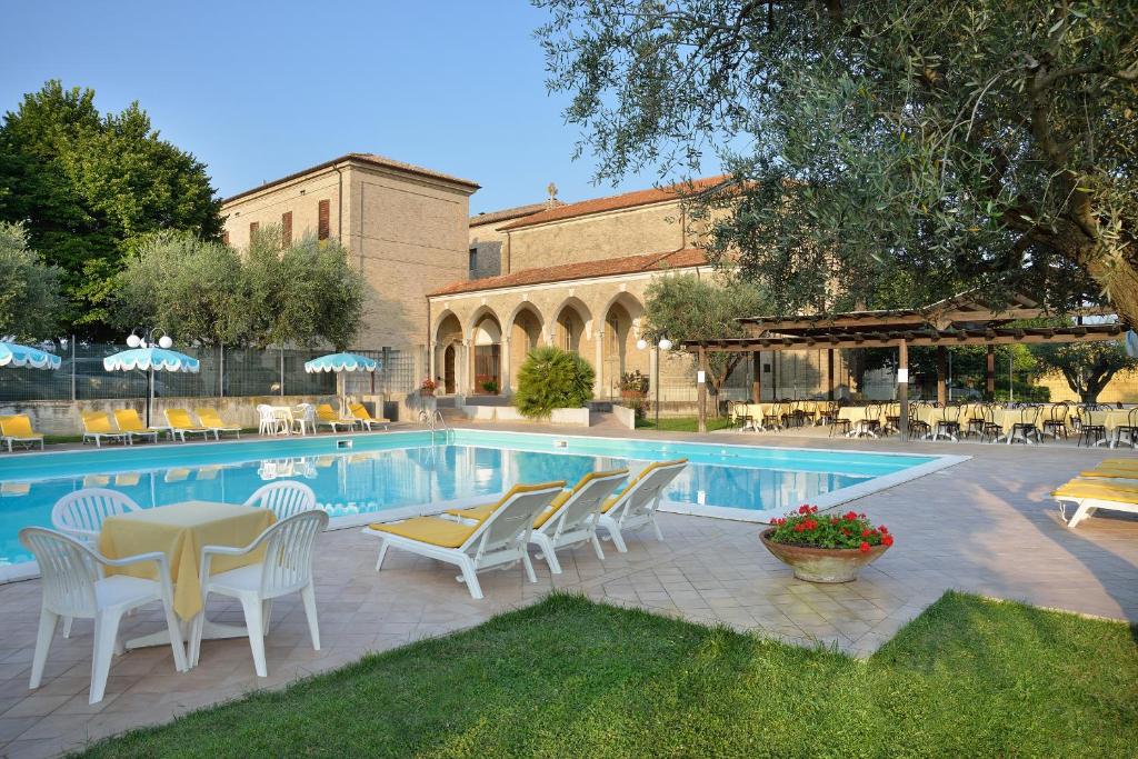 une piscine avec des chaises et une table à côté d'un bâtiment dans l'établissement Hotel Bel Sit, à Senigallia