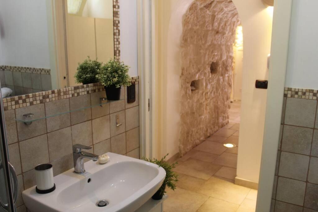 une salle de bain avec un lavabo et un mur en pierre dans l'établissement TRULLO CHEFMARCO PRIVATE/SALTWATER SWIMMING POOL, à San Michele Salentino