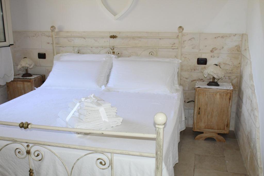 une chambre avec un lit blanc avec une tête de lit en bois dans l'établissement TRULLO CHEFMARCO PRIVATE/SALTWATER SWIMMING POOL, à San Michele Salentino 65 autres photos