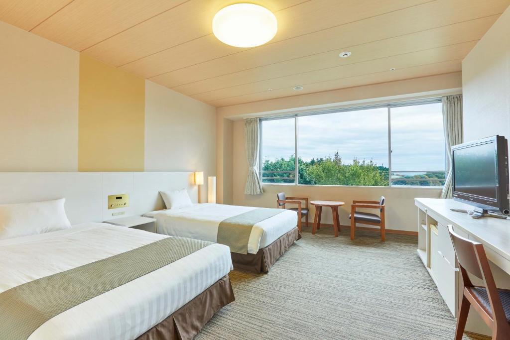 une chambre d'hôtel avec deux lits et une télévision à écran plat dans l'établissement KAMENOI HOTEL Kitsuregawa, à Sakura 85 autres photos