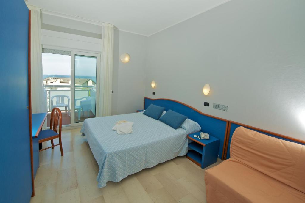 une chambre avec un lit bleu et un balcon dans l'établissement Hotel Torretta, à Cattolica