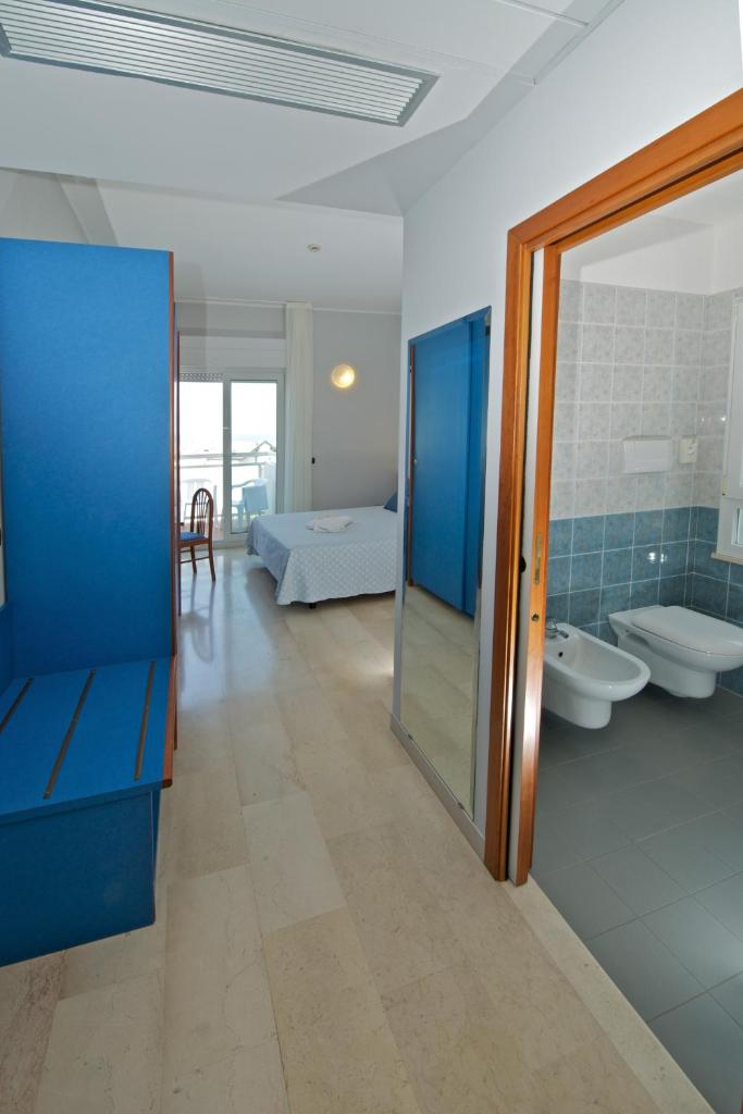 une salle de bains avec deux lavabos et une chambre avec un lit dans l'établissement Hotel Torretta, à Cattolica