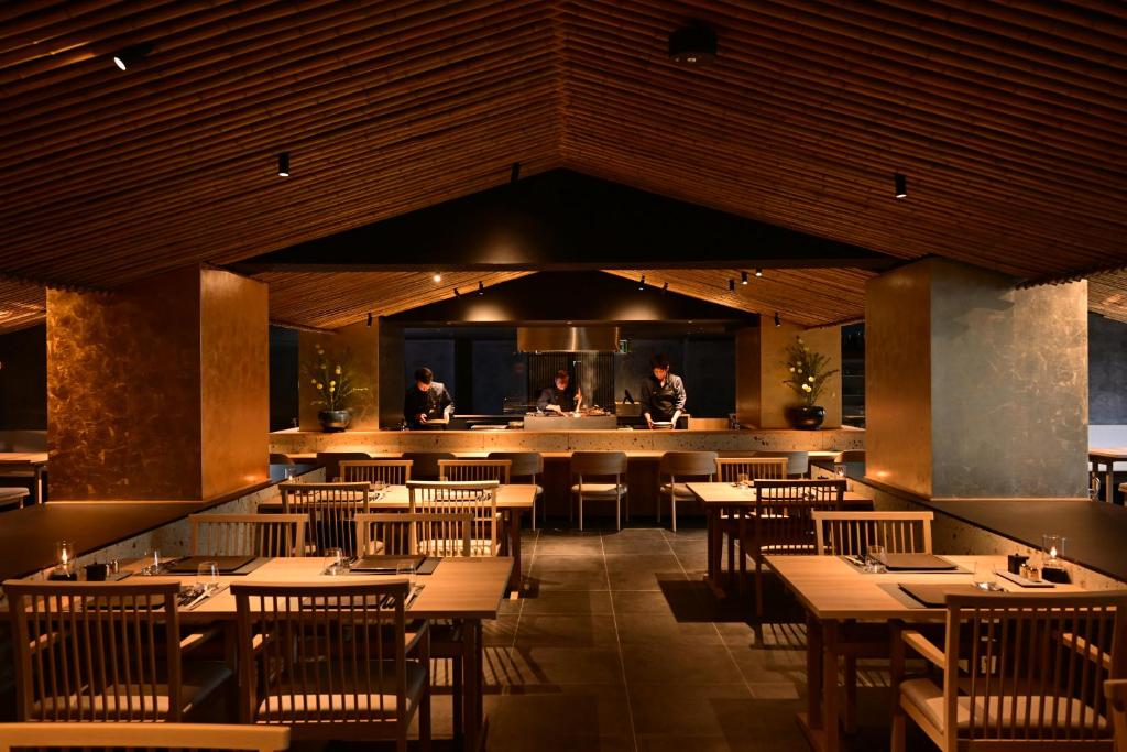 un restaurant avec des tables et des chaises en bois et un comptoir dans l'établissement Urakusatsu TOU, à Kusatsu