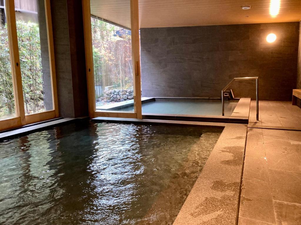 - une piscine d'eau dans une chambre avec fenêtres dans l'établissement Urakusatsu TOU, à Kusatsu