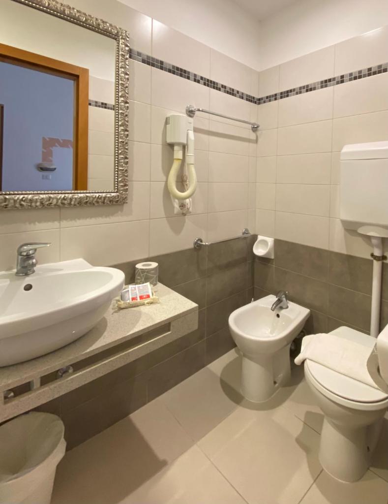 une salle de bain avec un lavabo, des toilettes et un miroir dans l'établissement Hotel Ravello Adults Only, à Rimini 63 autres photos