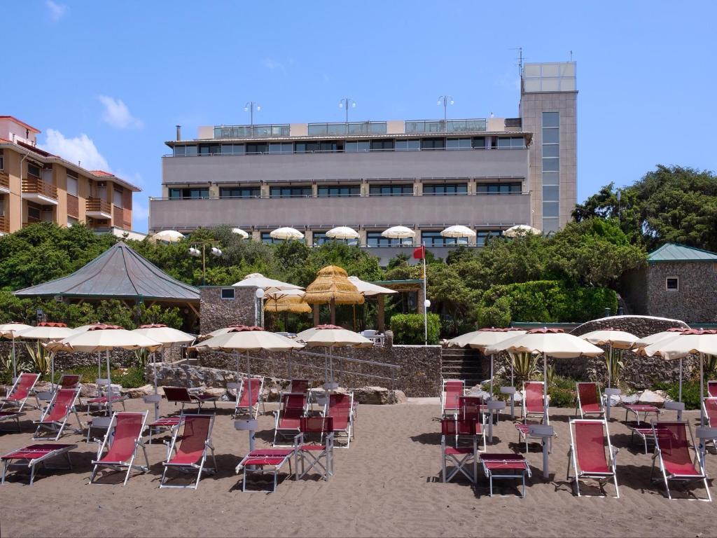 - un bouquet de chaises et de parasols sur une plage dans l'établissement Hotel I Ginepri, à Marina di Castagneto Carducci