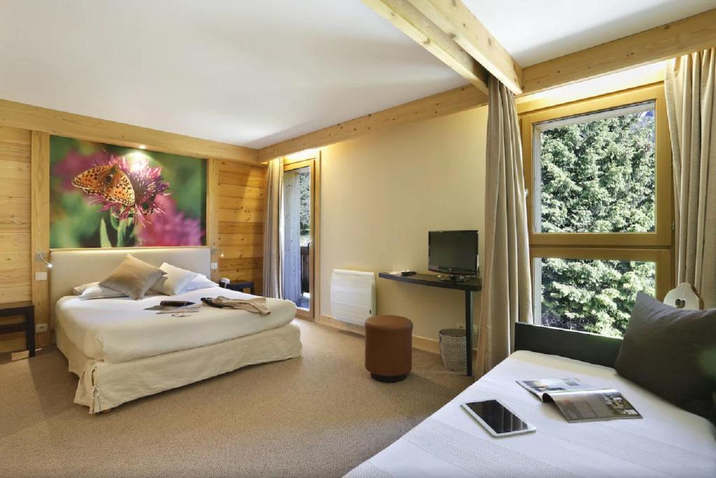une chambre d'hôtel avec deux lits et une télévision dans l'établissement Les Roches 1500, à Mieussy