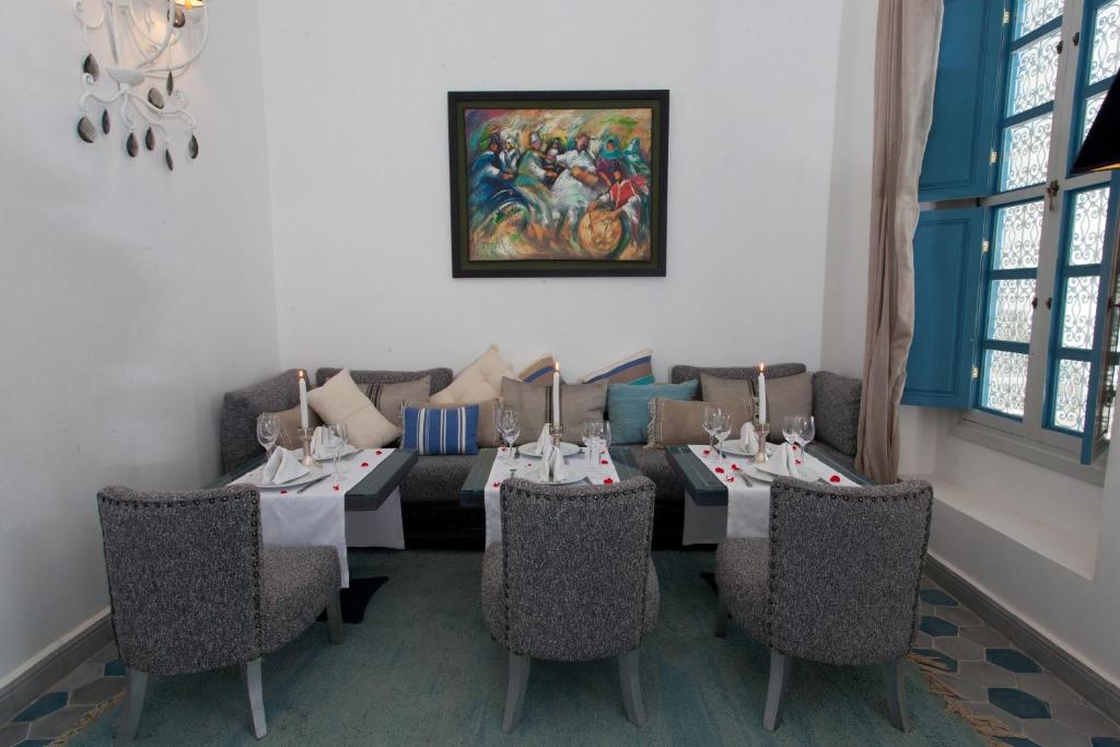une salle à manger avec des tables et des chaises ainsi qu'une peinture murale. dans l'établissement Riad Le Perroquet Bleu Suites & Spa, à Marrakech